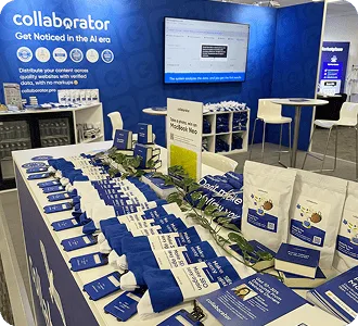 Stoisko Collaborator na BrightonSEO 2026 z firmowymi gadżetami, broszurami i ekranem prezentacyjnym.